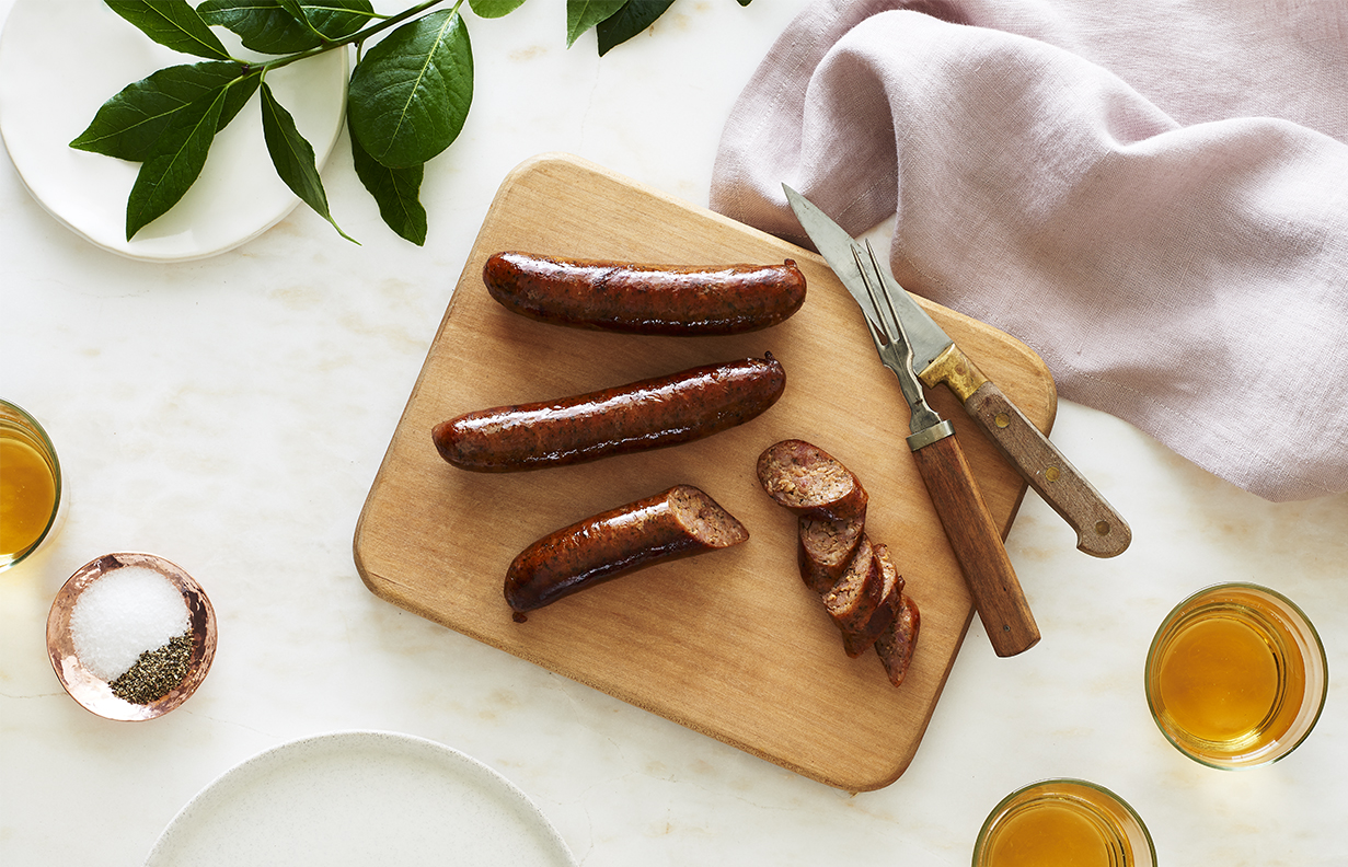Sausage links on cutting board with beer is food photography by Alison Gootee Photography