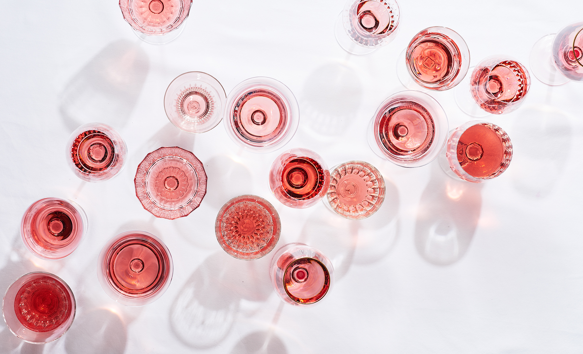 Overhead Glasses full of pink rose wine on white table clothe is food photography by Alison Gootee Photography