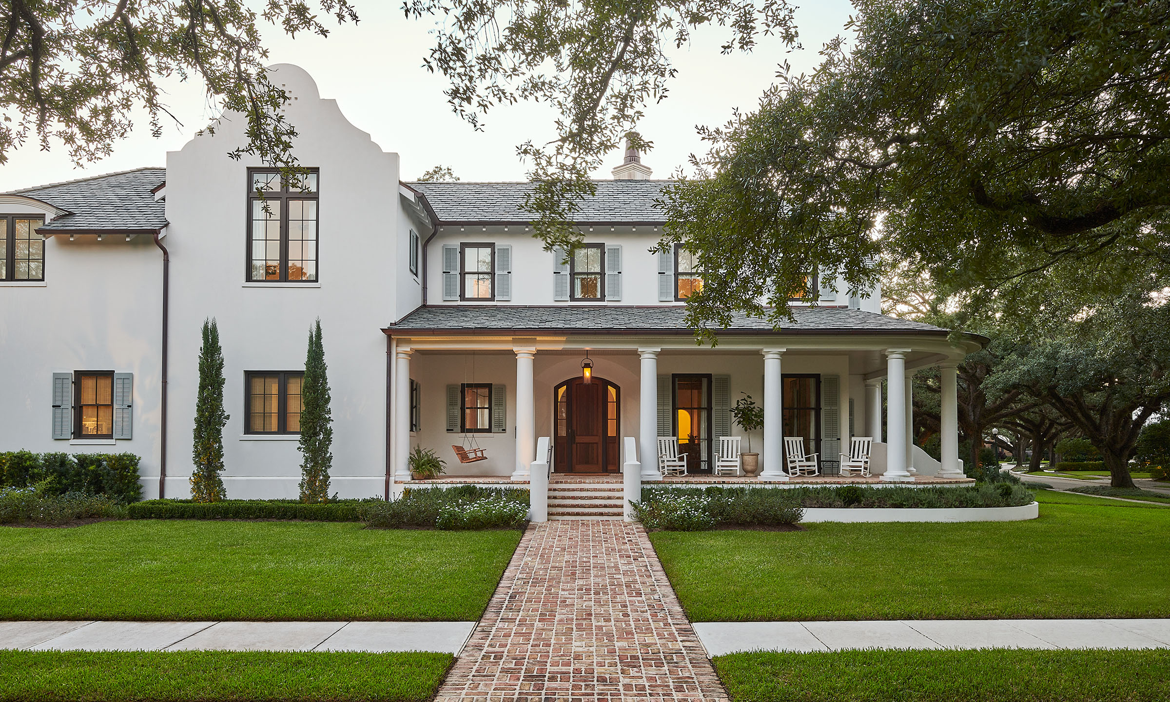 Exterior of white house with live oak trees and brick walkway and porch by Alison Gootee Photography for Logan Killen Interiors and BellArchitects