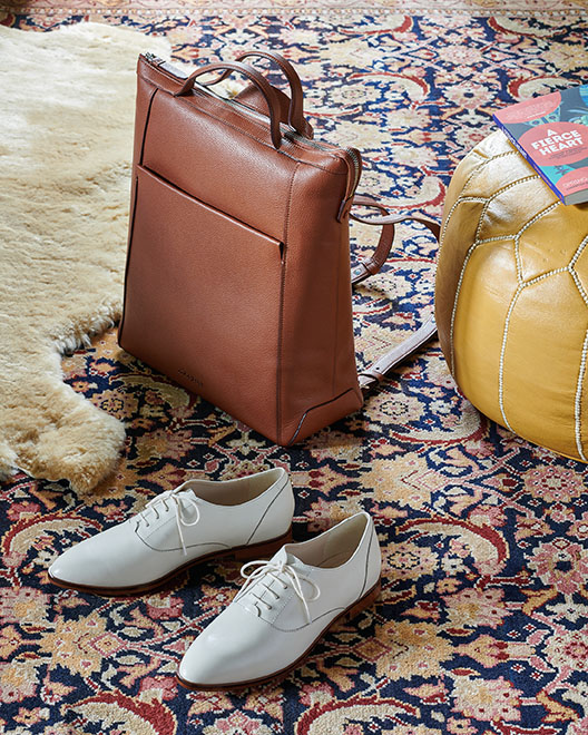 Brown leather backpack and white shoes on asian rug by Alison Gootee Photography 